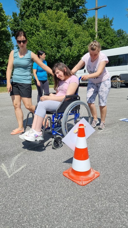 Sabina in Urška vozita Emo na vozičku po poligonu mimo stožca.