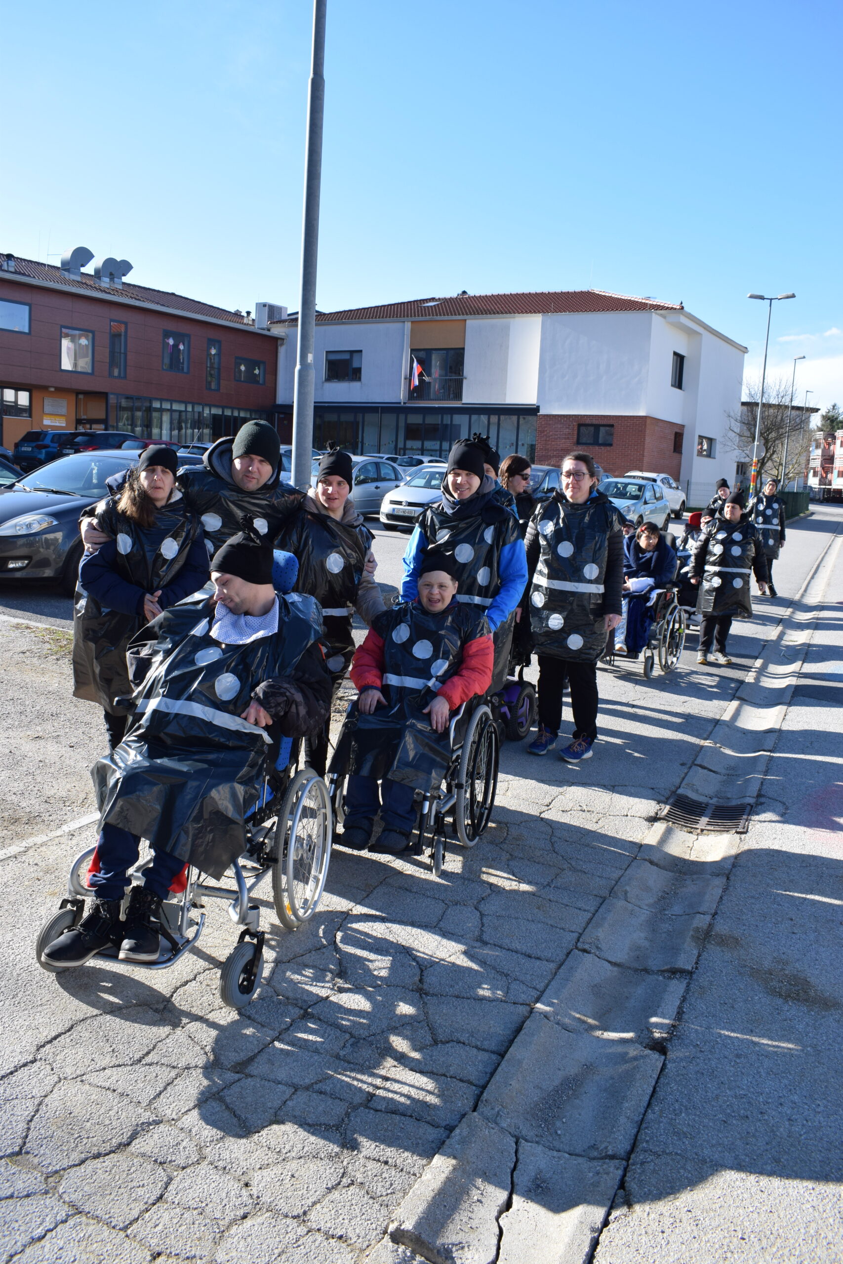 Skupina iz enote vipava gre po pločniku mimo vipavskega vrtca.