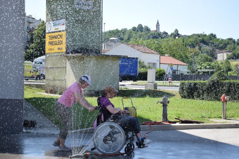Sabina pelje Emo čez vodno fontano.