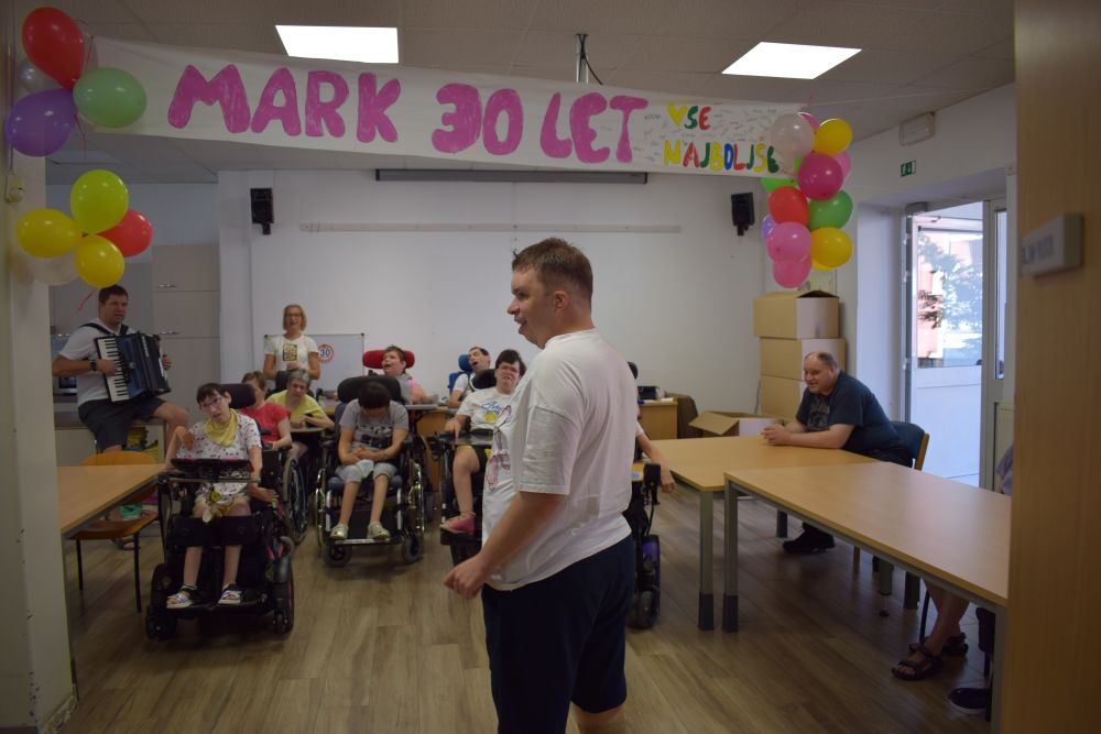 Mark stoji pod trasnparentom in posluša kako mu ostali pojejo.