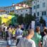 Trg v Vipavi, na njem Potujoča knjižnica in veliko otrok in uporabnikov VDC-ja. Na majhnem odru lahko vidimo Damjano Golavšek.