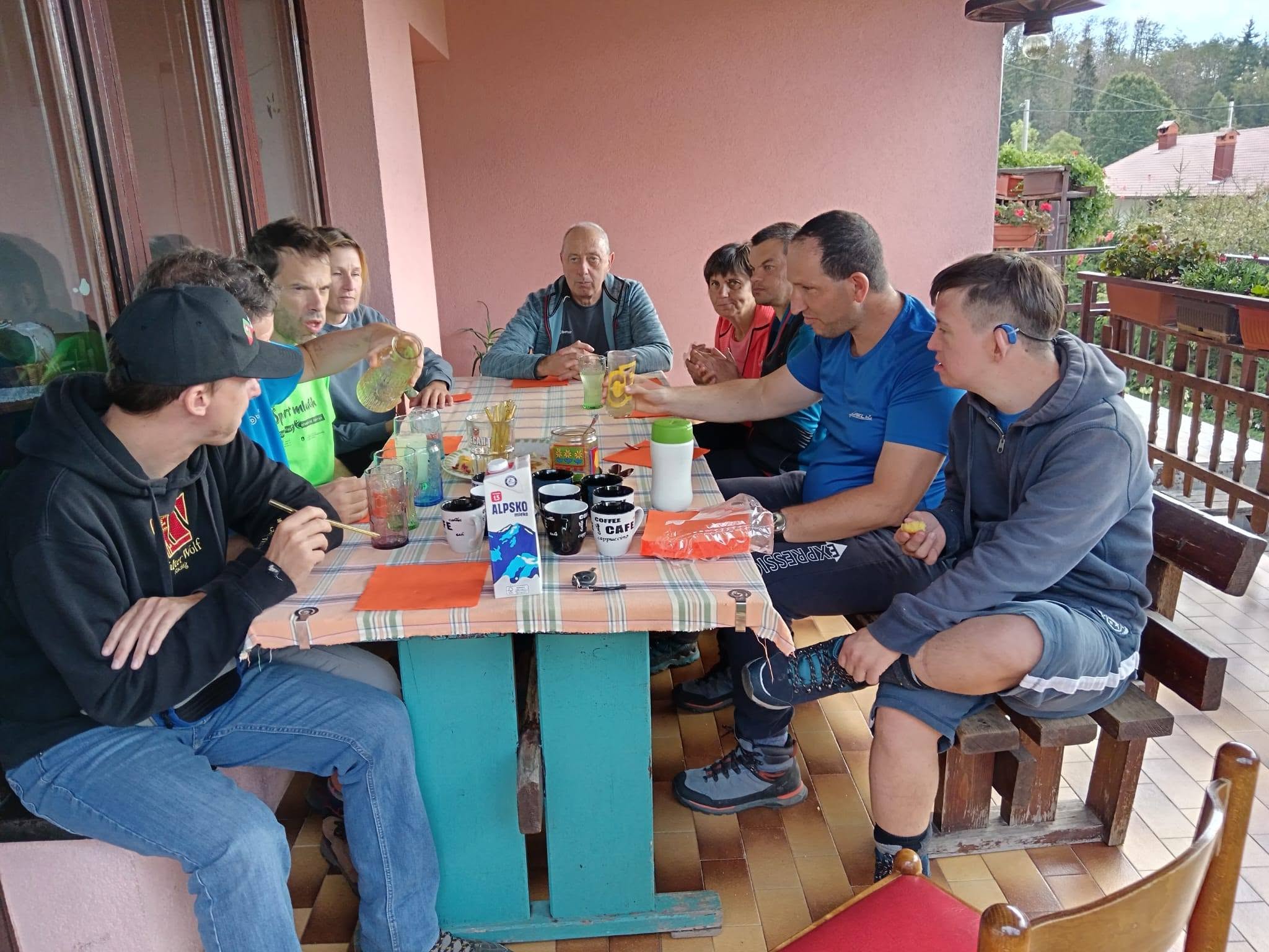 Družina našega pohodnika Janeza Rudolva je celo skupino povabila v goste na kavico. Ob mizi na terasi so vsi zbran iob kavi.